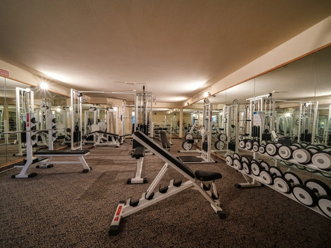 Sala fitness attrezzata con pesi, panche e macchinari per l'allenamento