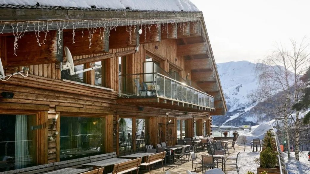 Facciata in legno dello chalet con terrazza, balconi e vista sulle montagne