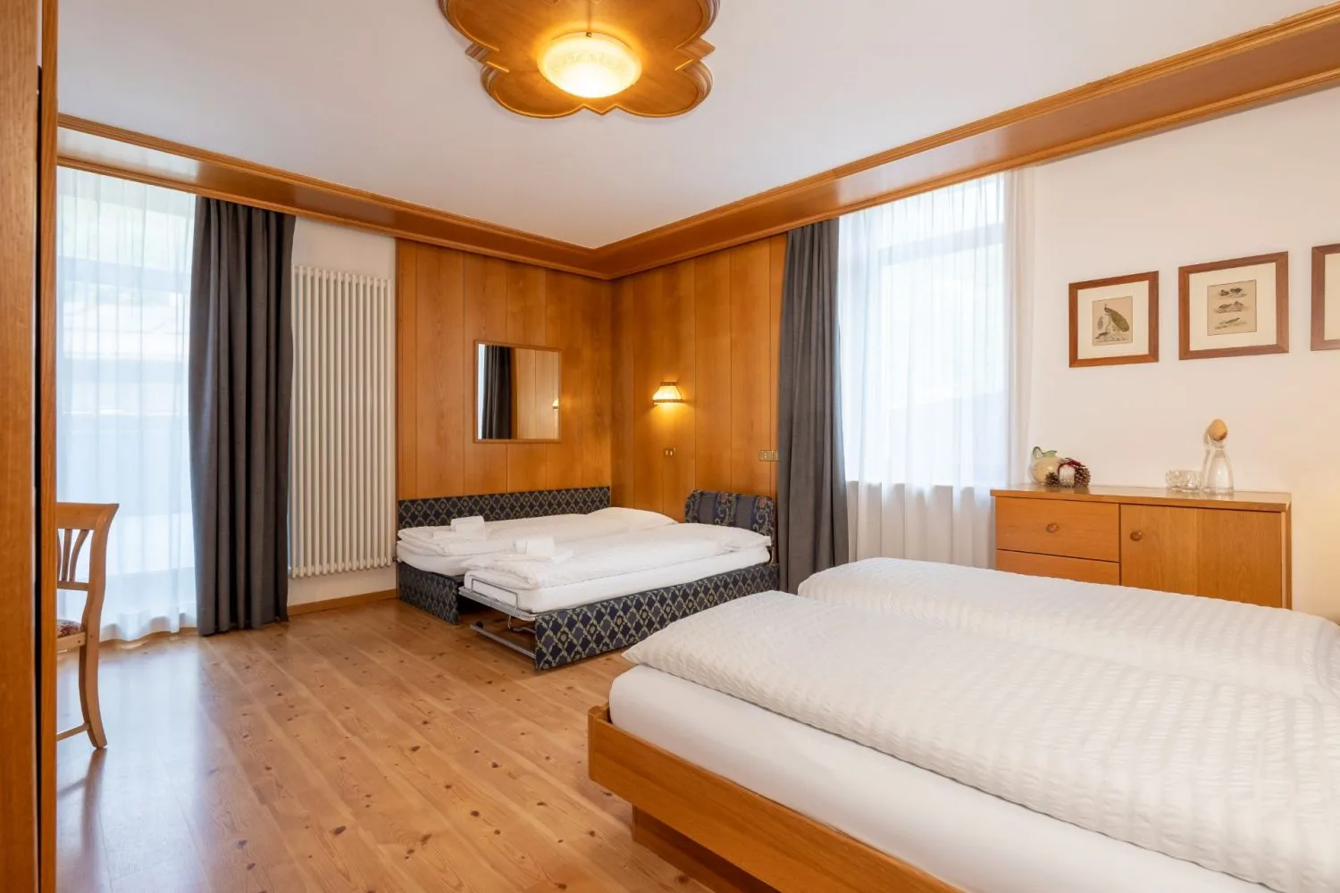 Camera spaziosa con rivestimenti in legno, letto matrimoniale e letto aggiunto