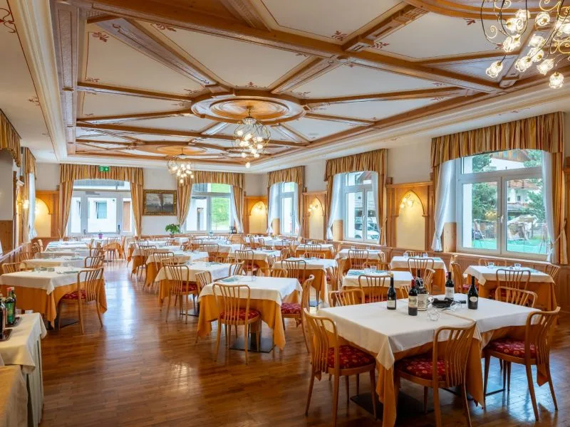 Sala ristorante elegante con tavoli apparecchiati e soffitto a cassettoni in legno