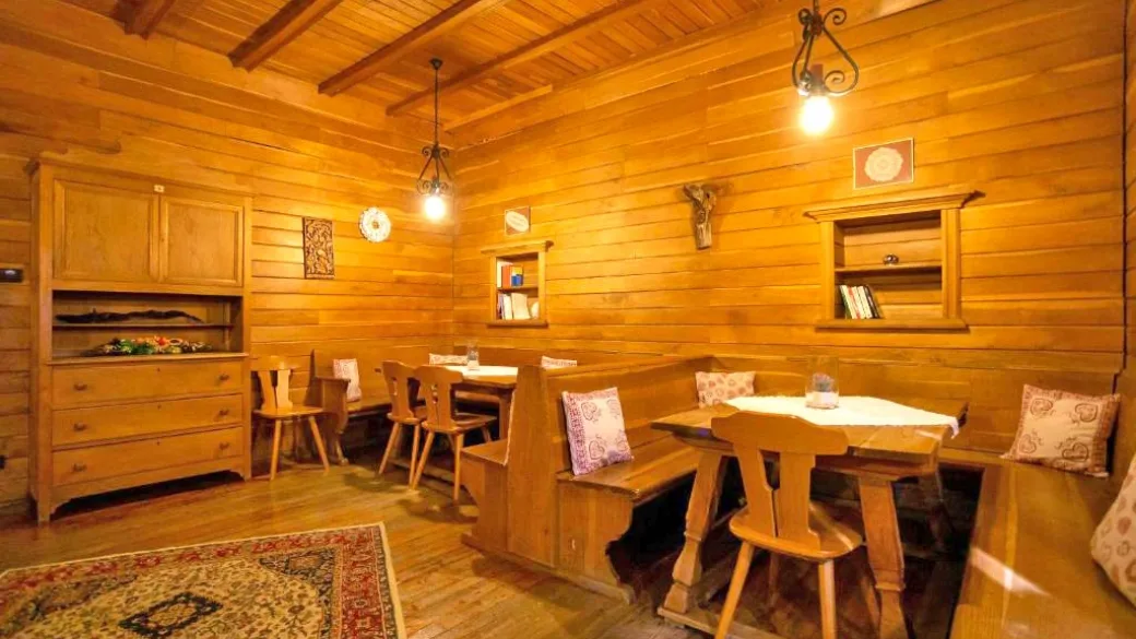 Accogliente stube rivestita in legno con tavoli, panche e cuscini decorativi