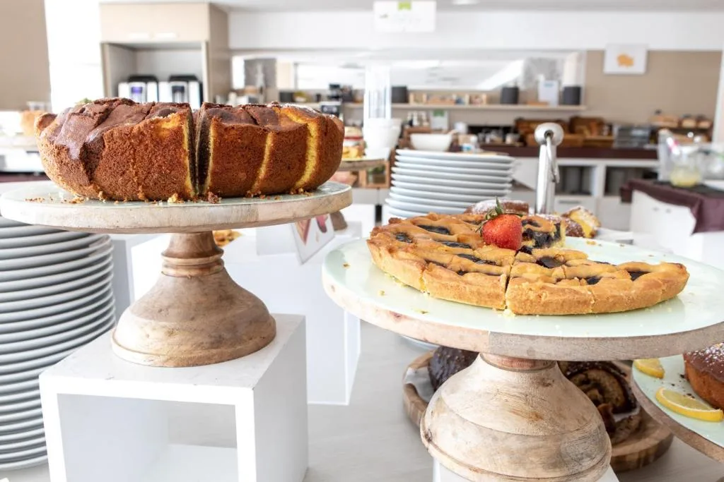 Buffet della colazione con torte e crostate su alzate di legno