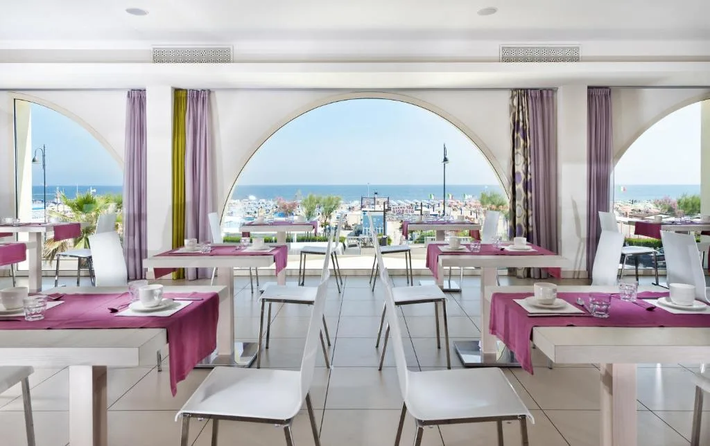 Sala ristorante con grandi archi e vista mare, tavoli apparecchiati con tovaglie viola