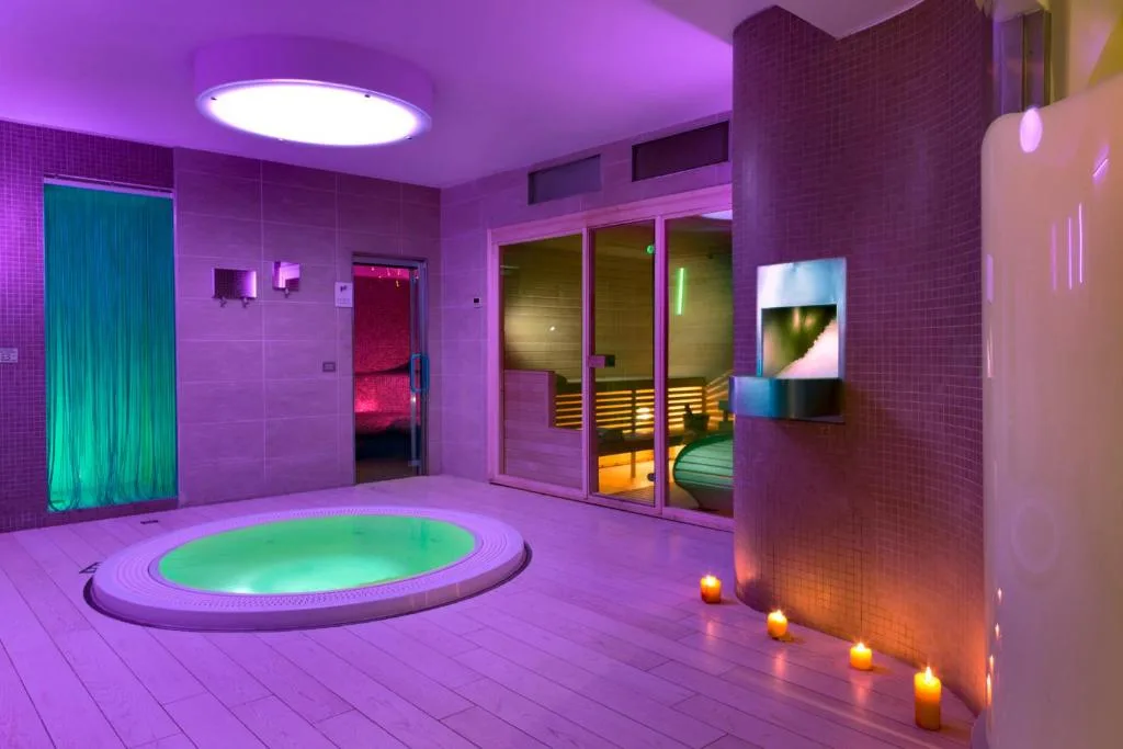 Area benessere con idromassaggio e sauna con luci viola e candele