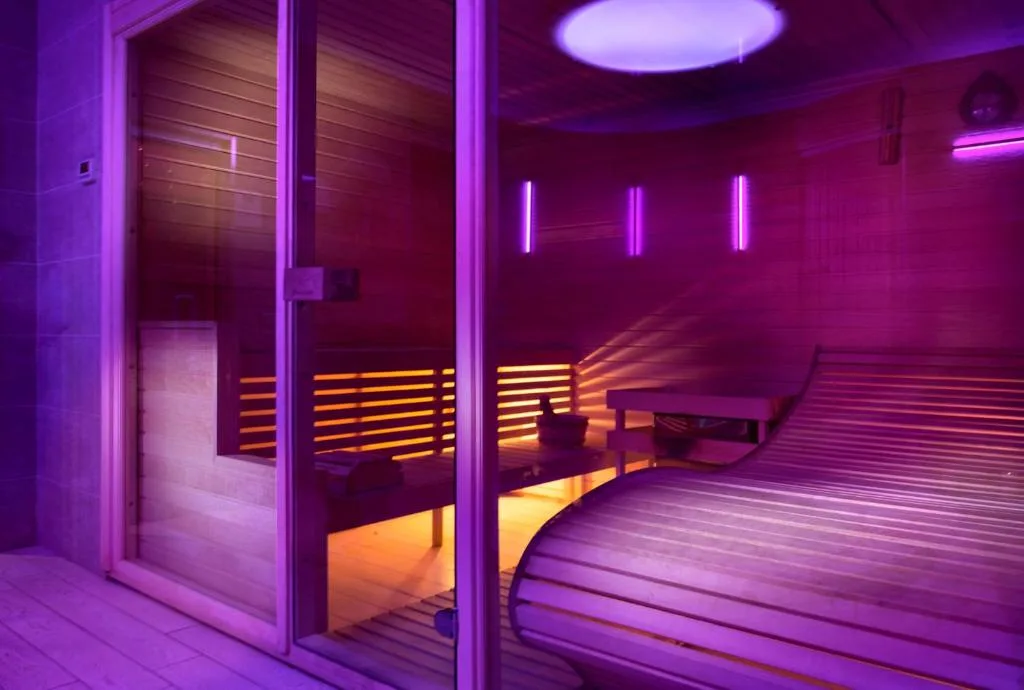 Sauna in legno illuminata con luci viola e arancioni