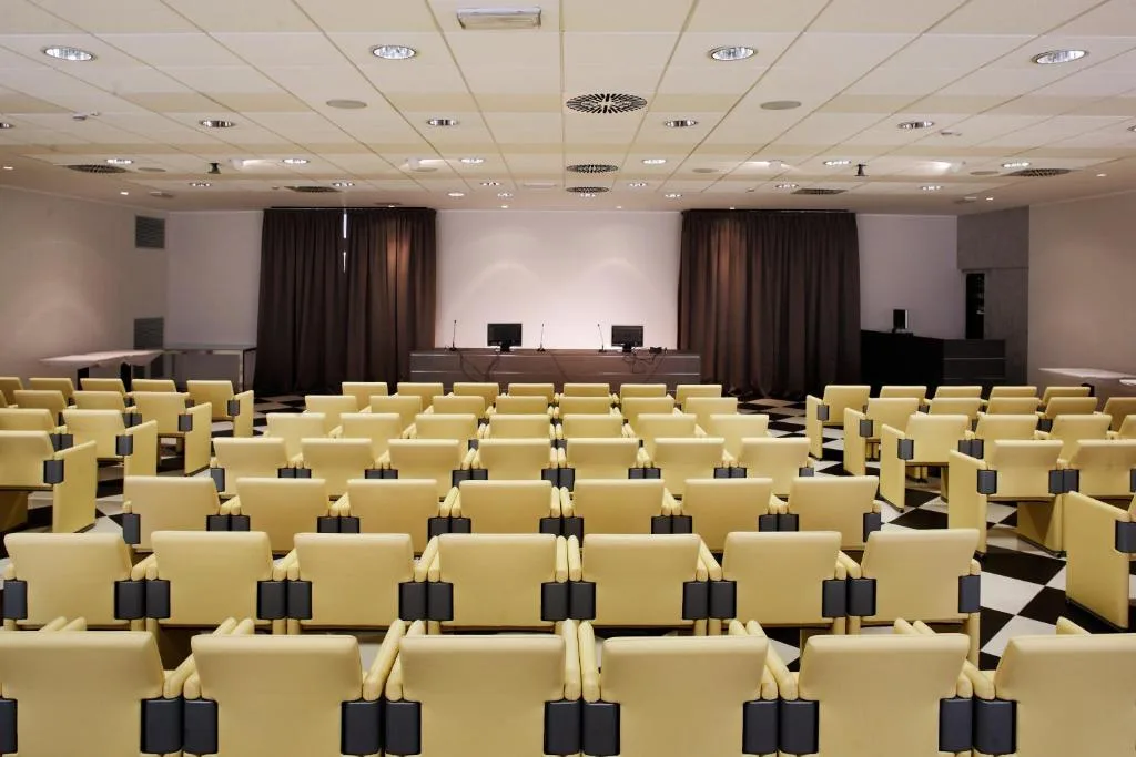 Sala conferenze con poltrone gialle e pavimento a scacchi