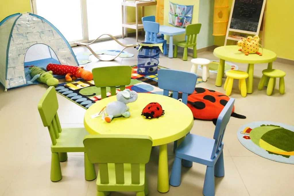 Area ludica per bambini con tende, peluche e tavolini colorati