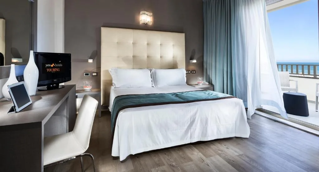 Camera elegante con letto matrimoniale, scrivania e vista mare dal balcone