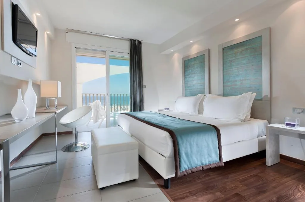 Camera moderna bianca con letto matrimoniale e balcone con vista mare