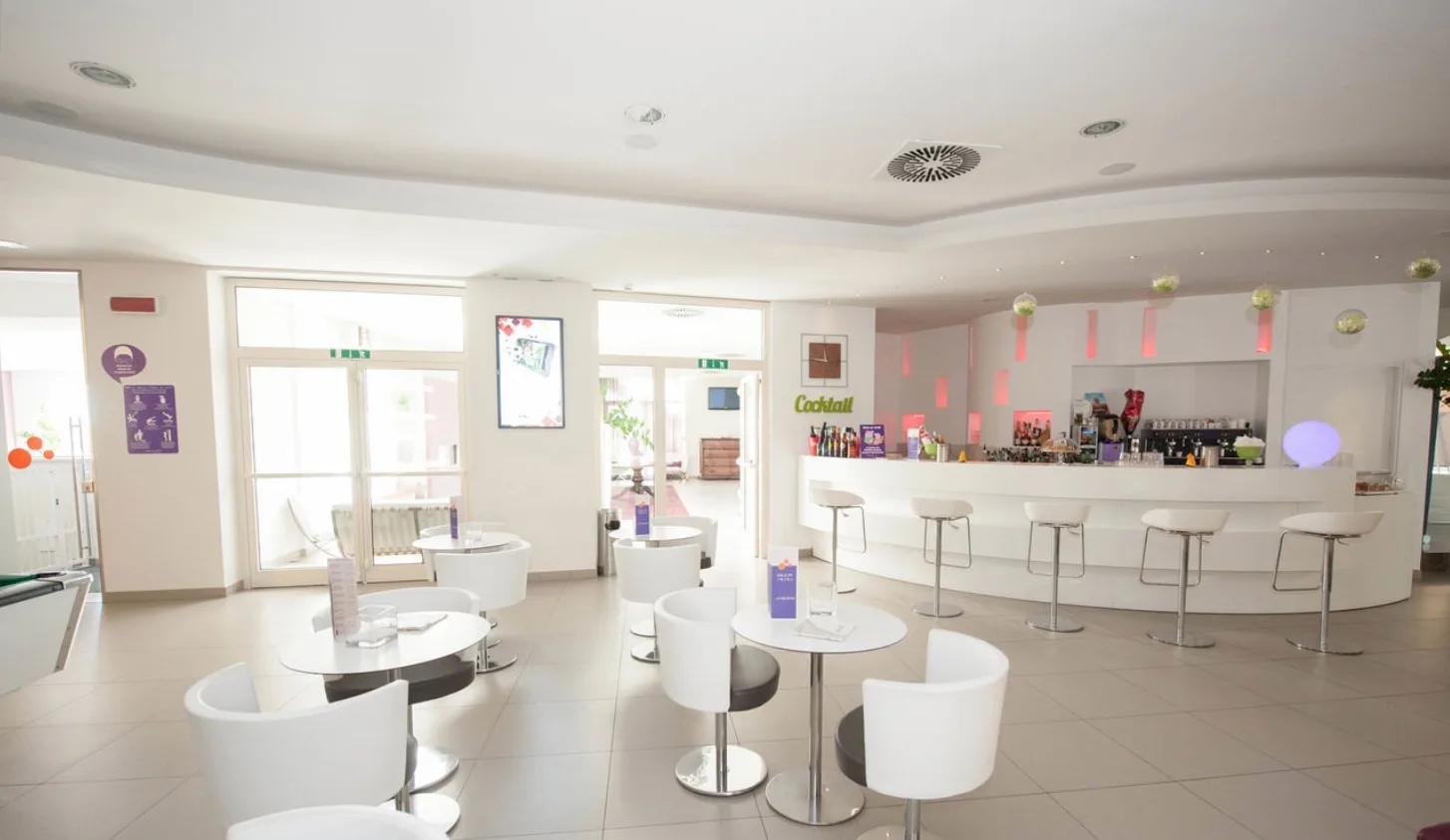 Bar interno dell'hotel con bancone bianco e sedute moderne