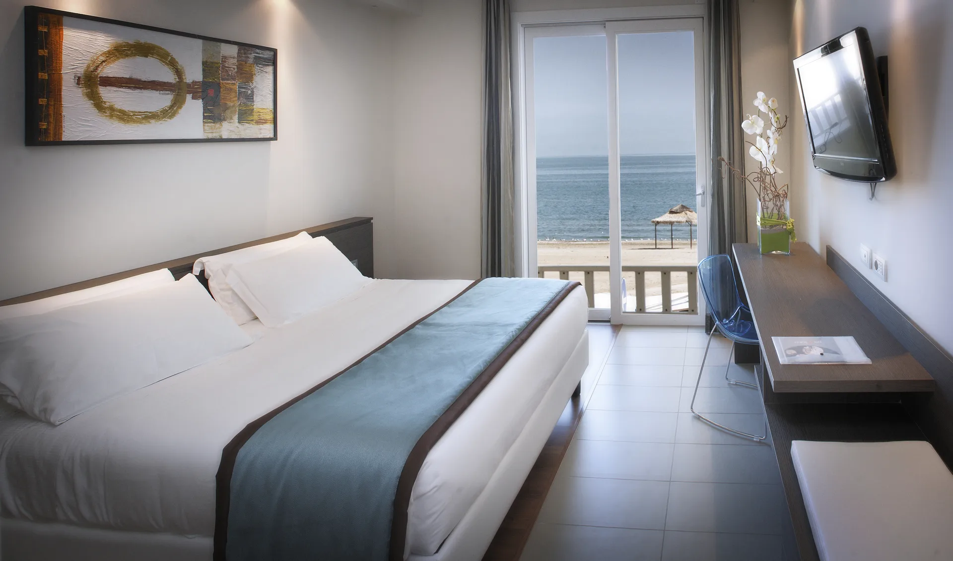 Camera moderna con letto matrimoniale e balcone affacciato sulla spiaggia