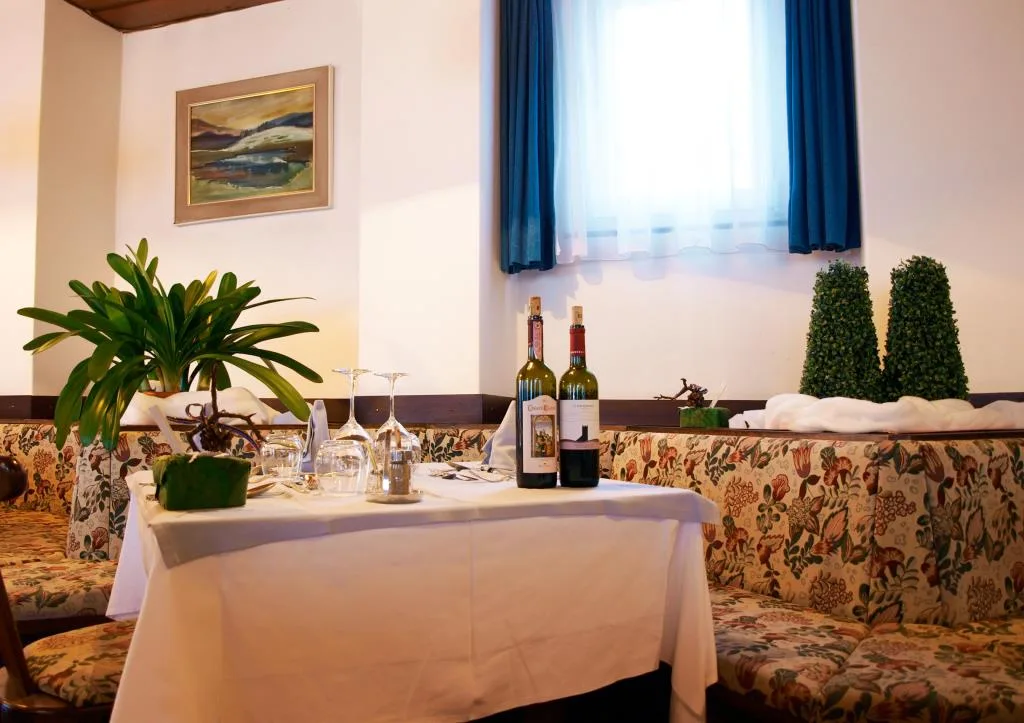 Tavolo del ristorante apparecchiato con tovaglia bianca e bottiglie di vino