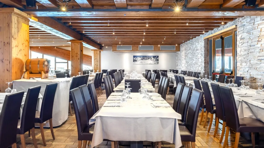 Sala ristorante in stile alpino con pareti in pietra, botte in legno e tavoli apparecchiati