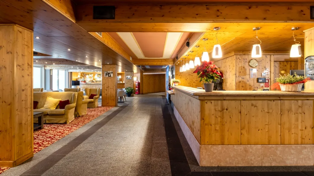 Hall dell'hotel con reception in legno, poltrone e illuminazione calda