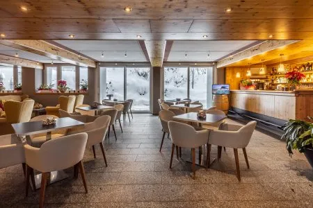 Sala lounge con poltrone, tavolini e vetrate affacciate sulla neve