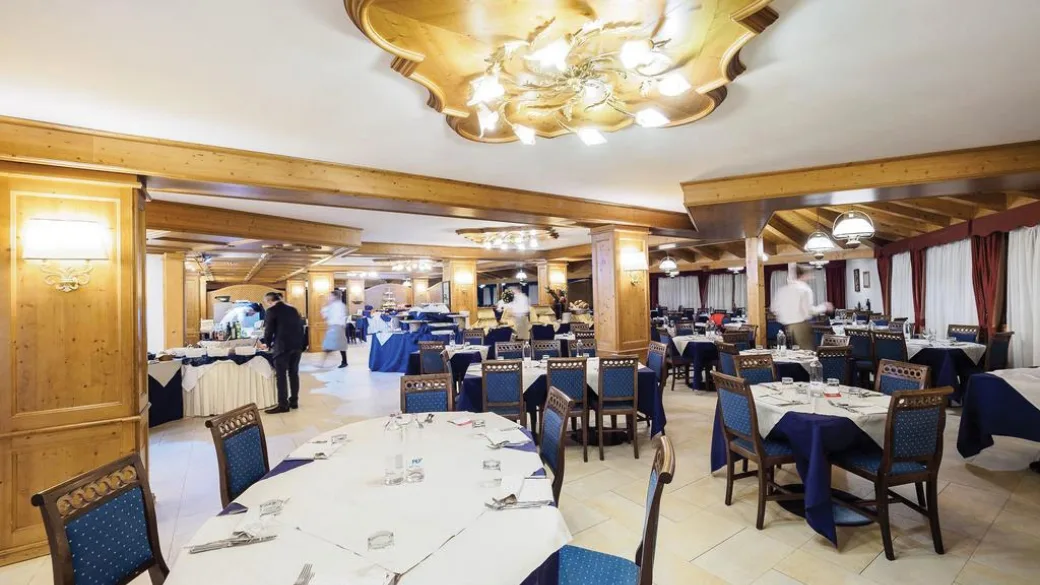 Sala ristorante elegante con tavoli apparecchiati, tovaglie blu e boiserie in legno