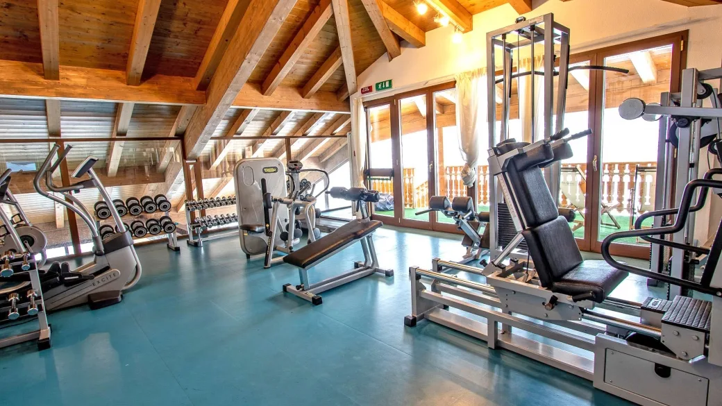 Palestra attrezzata con macchinari, pesi e soffitto in legno a vista
