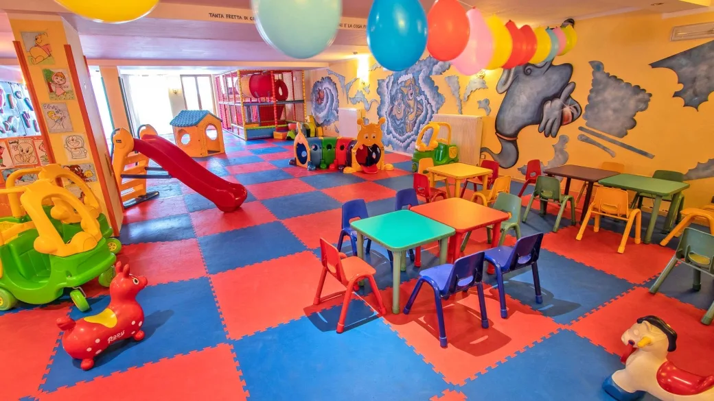 Sala giochi per bambini colorata con scivolo, tavolini e giochi