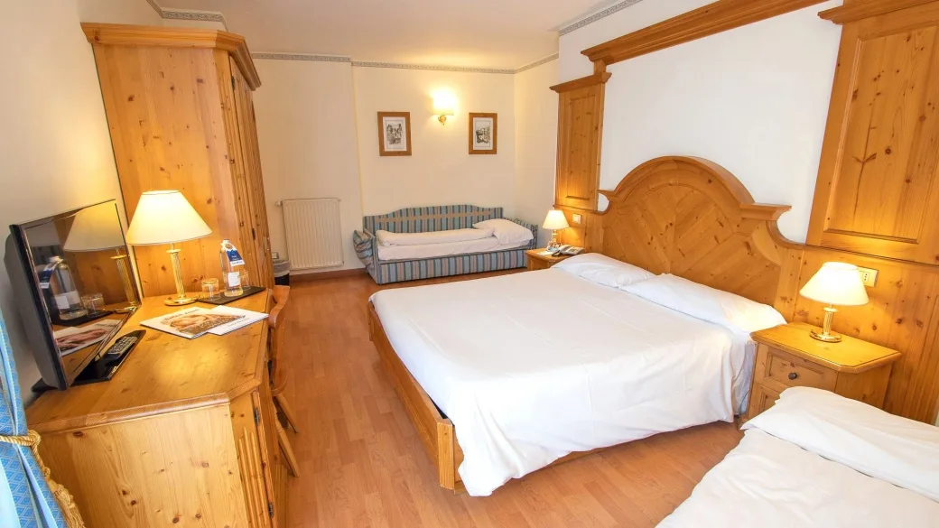 Camera classica con letto matrimoniale, mobili in legno di pino e TV