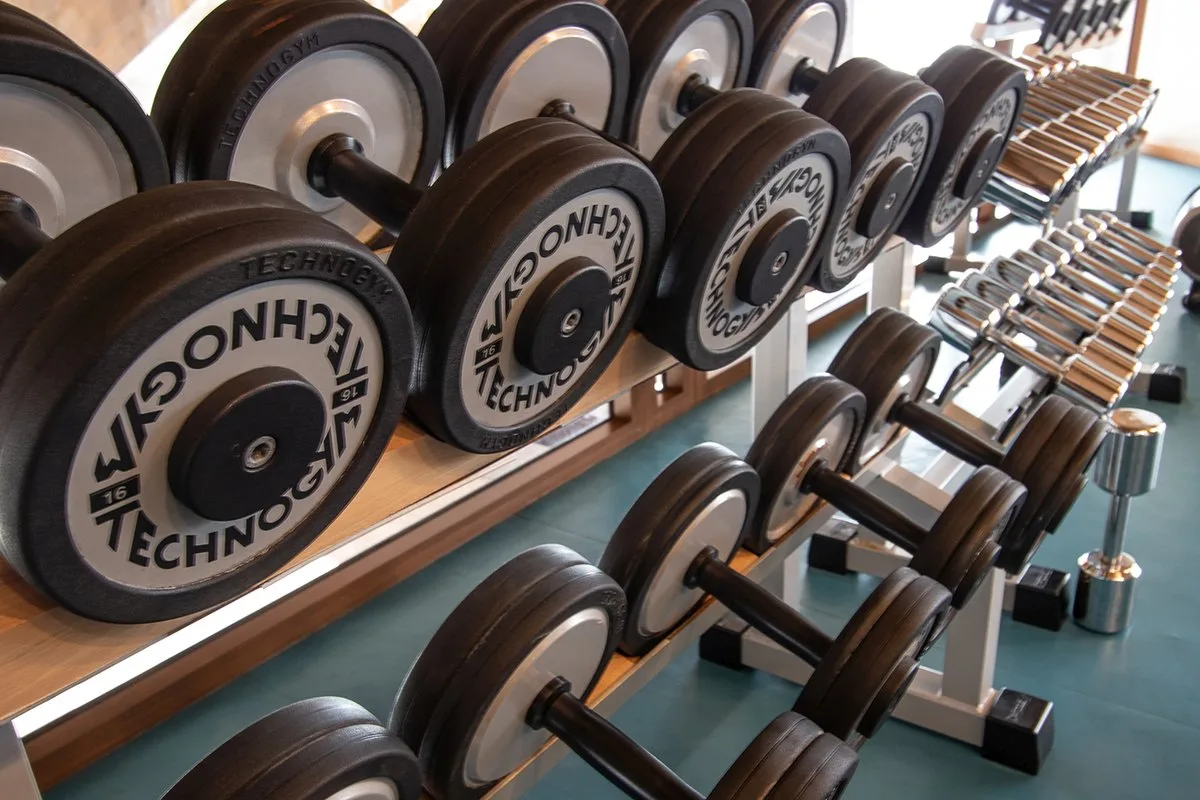 Set di manubri Technogym allineati su rastrelliera nella palestra dell'hotel