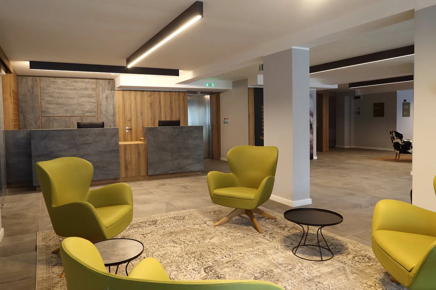 Reception dell'hotel con banco in pietra e legno e poltrone gialle