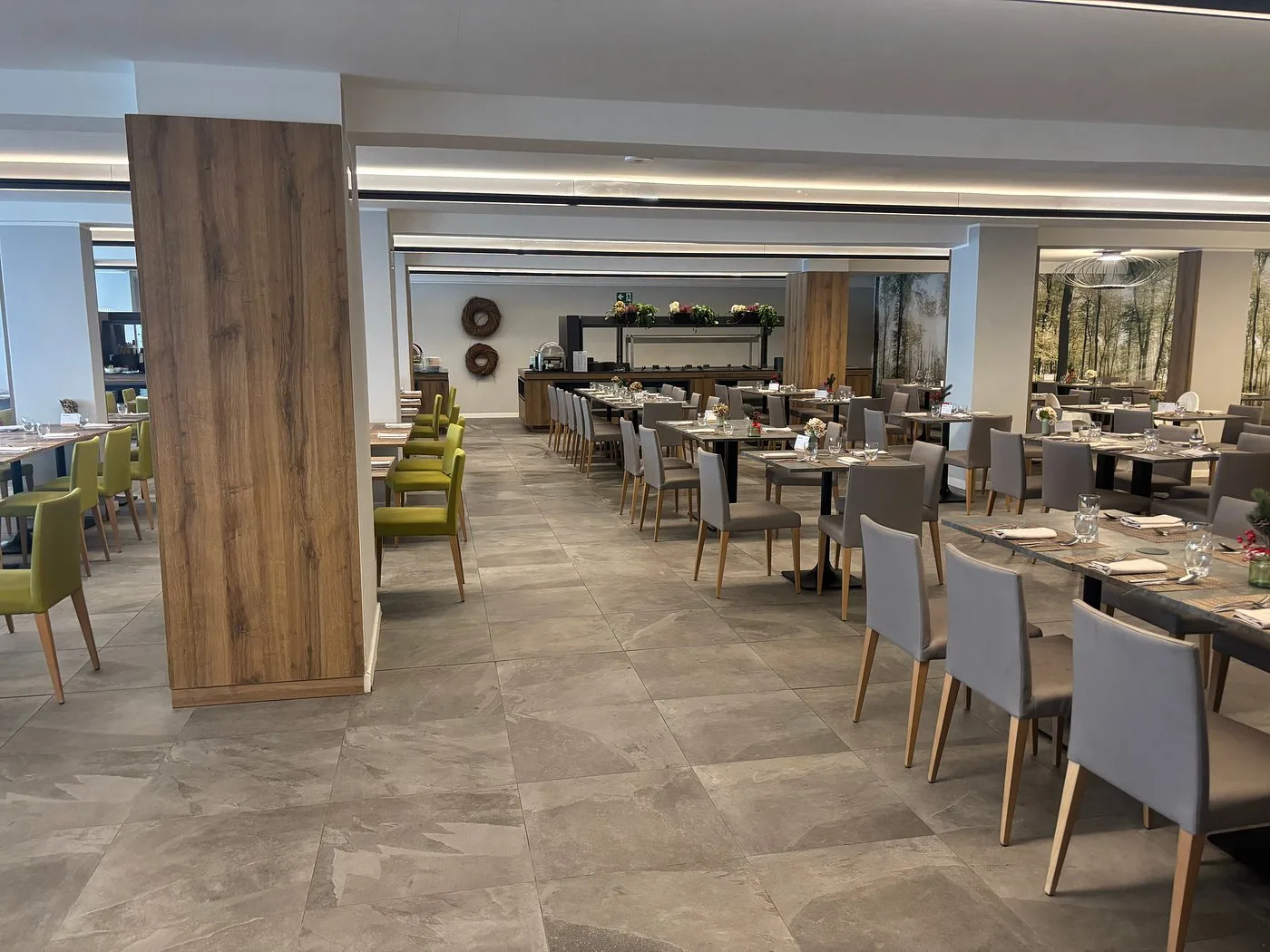 Sala ristorante con tavoli apparecchiati e sedie grigie e verdi