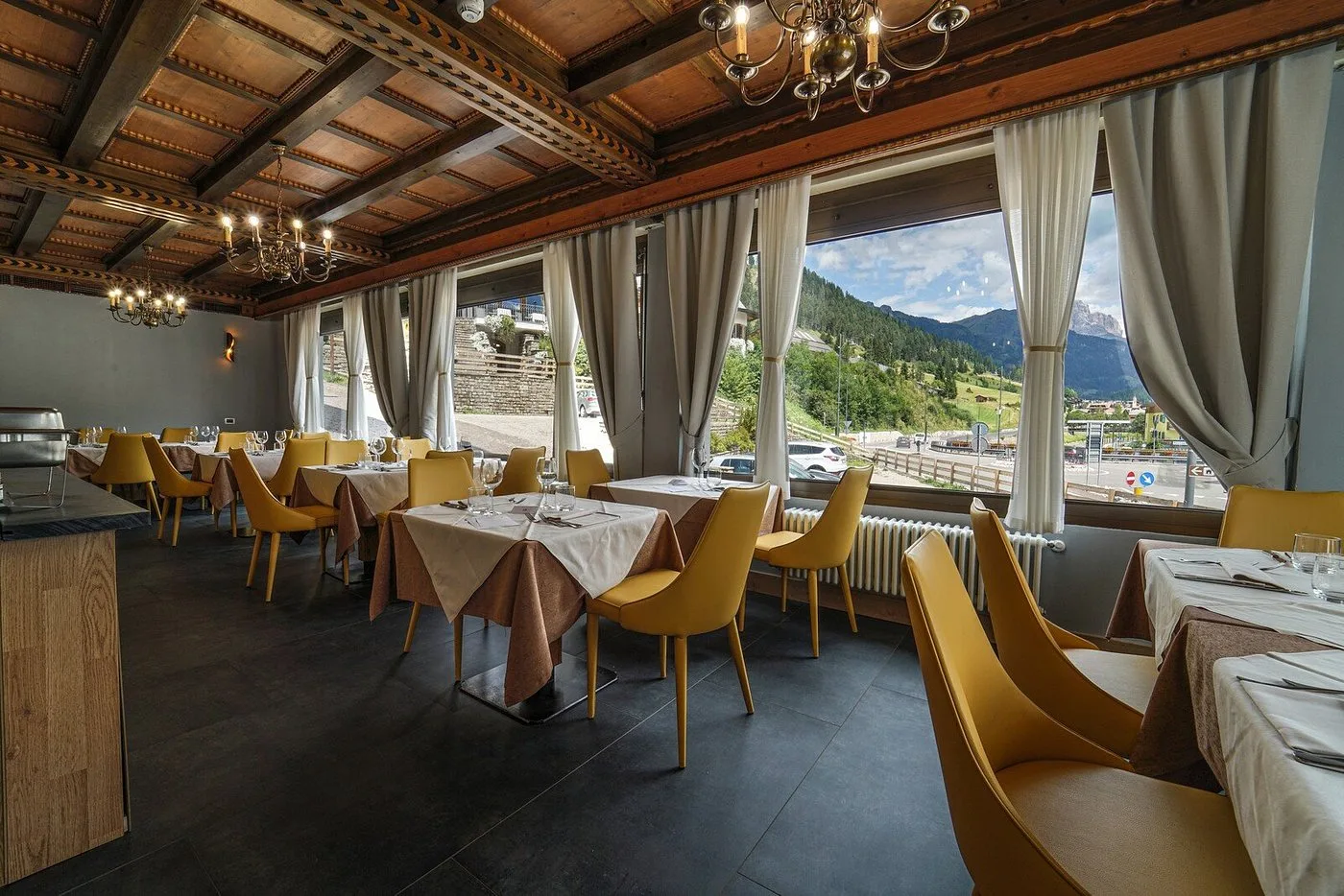 Sala ristorante con soffitto in legno, lampadari e ampie finestre sulle montagne