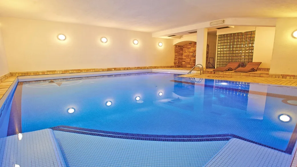 Piscina coperta con illuminazione soffusa e lettini per il relax