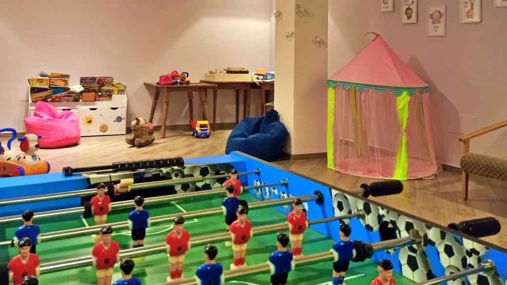 Sala giochi per bambini con calcio balilla, giocattoli e tenda rosa