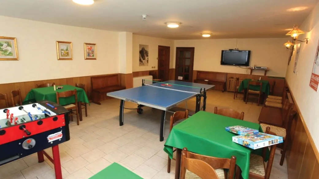Sala giochi con tavolo da ping pong, calcio balilla e tavoli con tovaglie verdi
