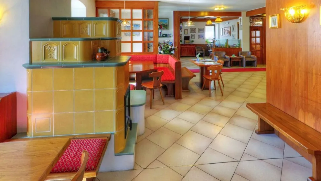 Soggiorno dell'hotel con caratteristica stufa in maiolica gialla e arredi in legno