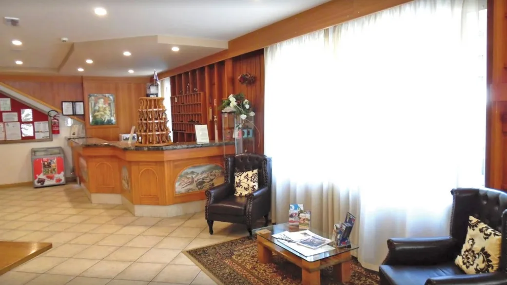 Reception dell'hotel con bancone in legno e poltrone in pelle