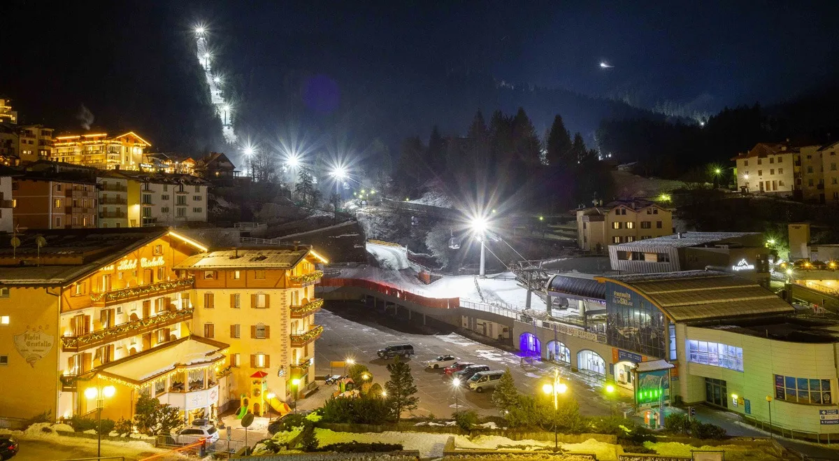 Vista notturna della località montana illuminata con impianti sciistici