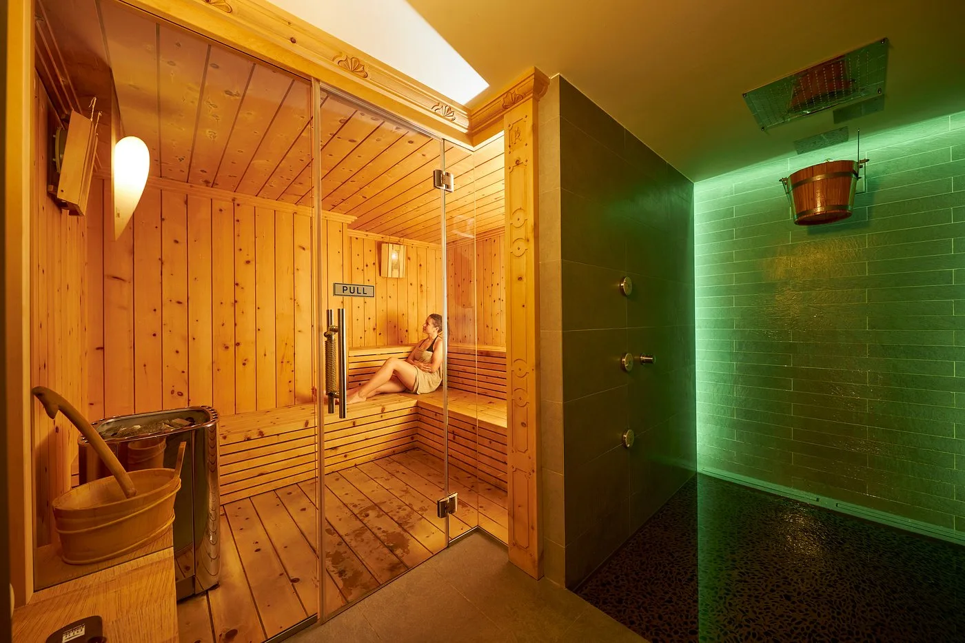 Sauna finlandese con ospite all'interno e doccia con luce verde