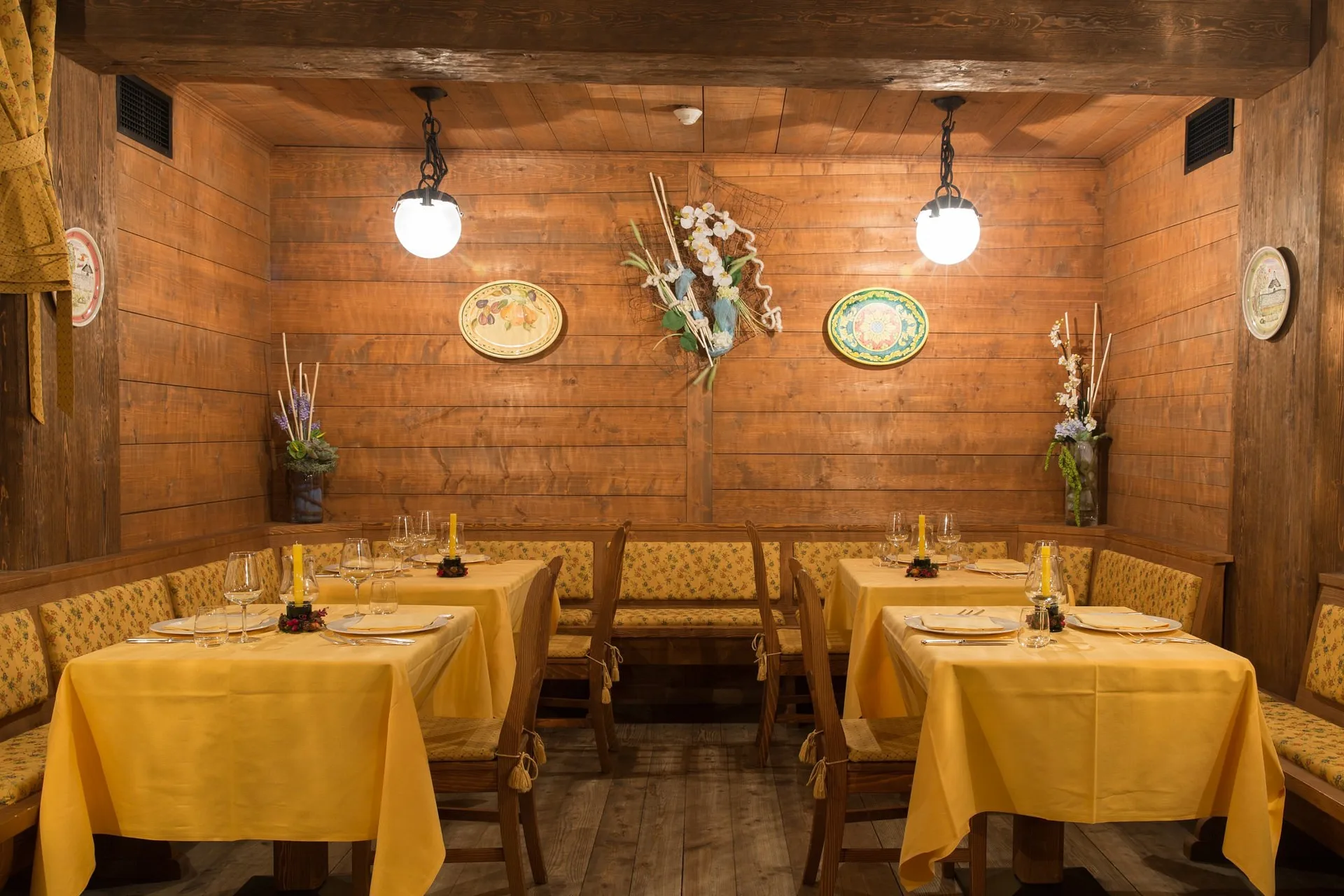 Saletta ristorante rustica con pareti in legno e tovaglie gialle