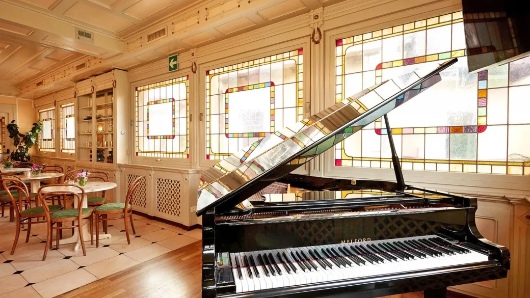 Sala con pianoforte a coda e vetrate artistiche colorate in stile liberty