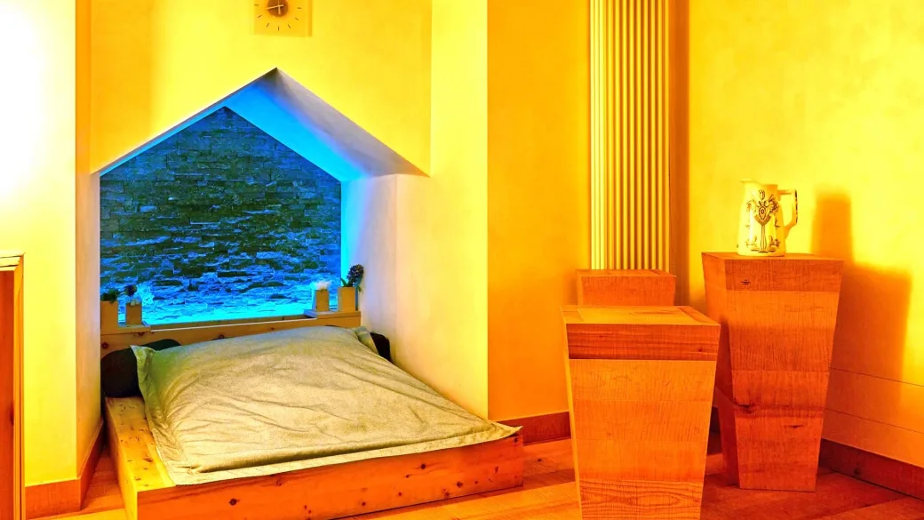 Area relax della spa con lettino e parete illuminata in pietra blu