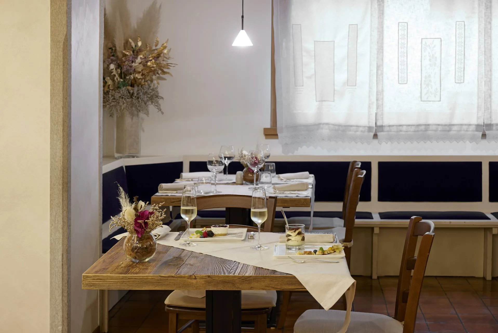 Sala ristorante con tavoli in legno, dessert e decorazioni floreali