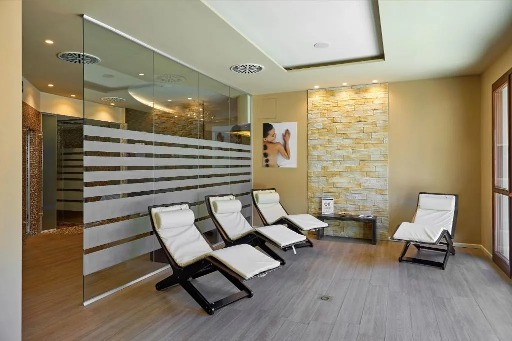 Zona relax della spa con lettini bianchi e parete in pietra illuminata