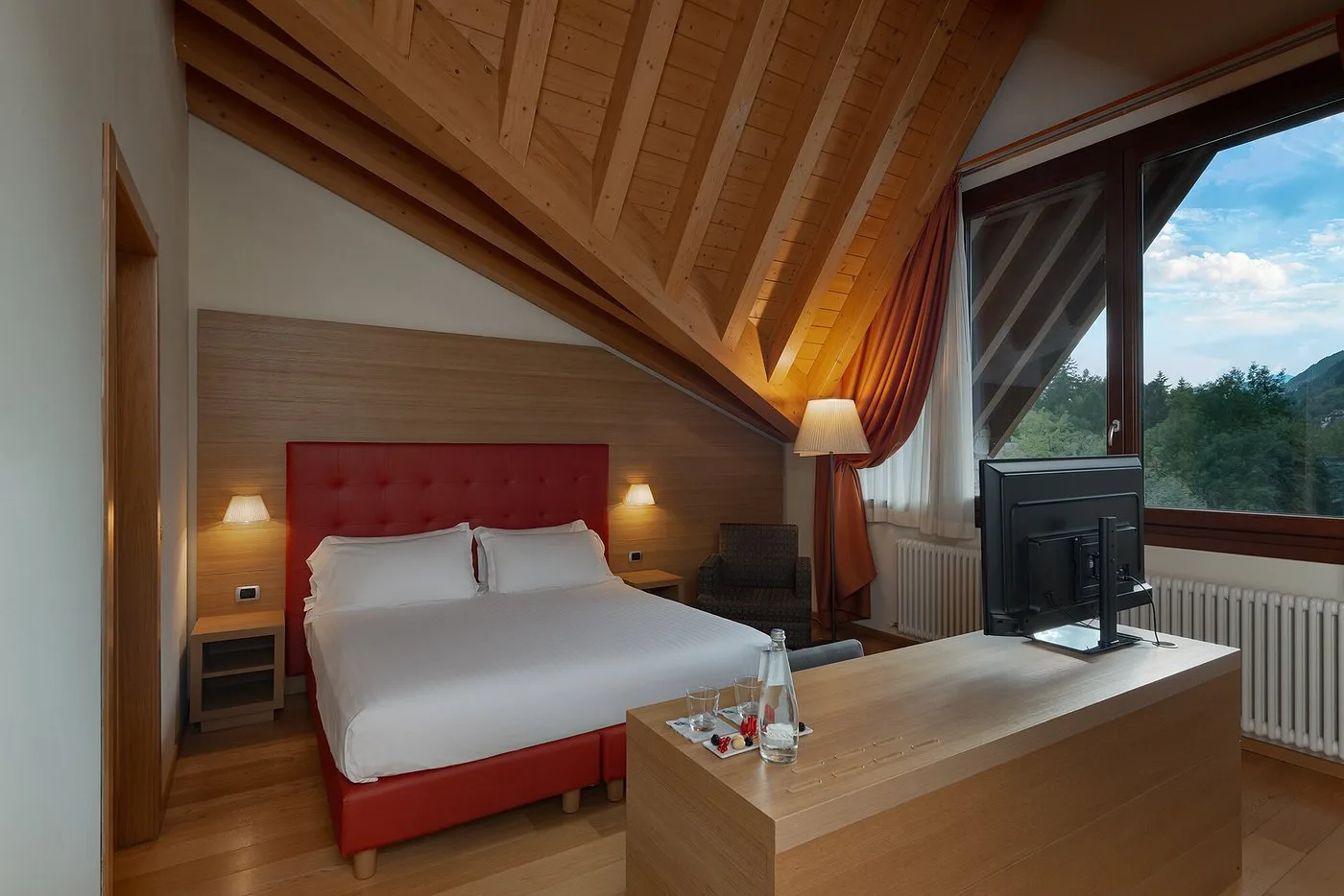 Camera mansardata con letto matrimoniale e ampia finestra con vista sulle montagne