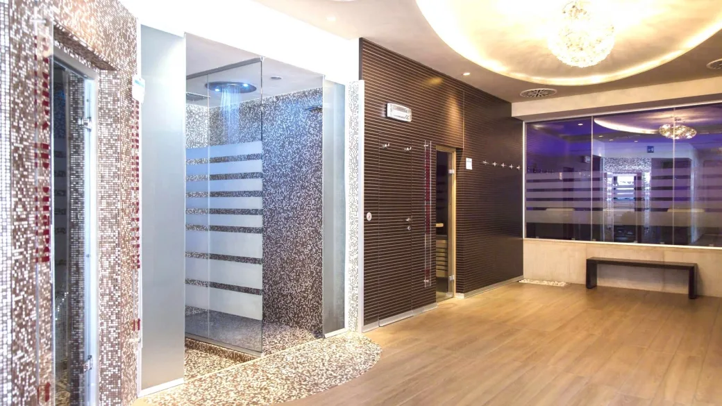 Area benessere con docce emozionali in mosaico e sauna in vetro