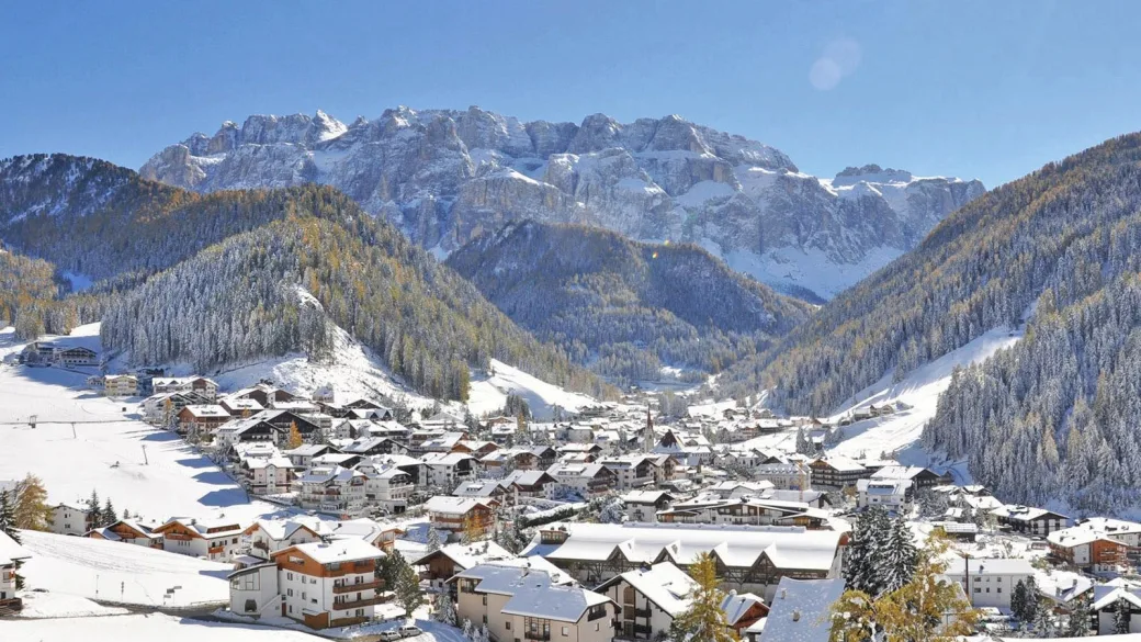 Panorama di un villaggio alpino innevato circondato da boschi e montagne delle Dolomiti