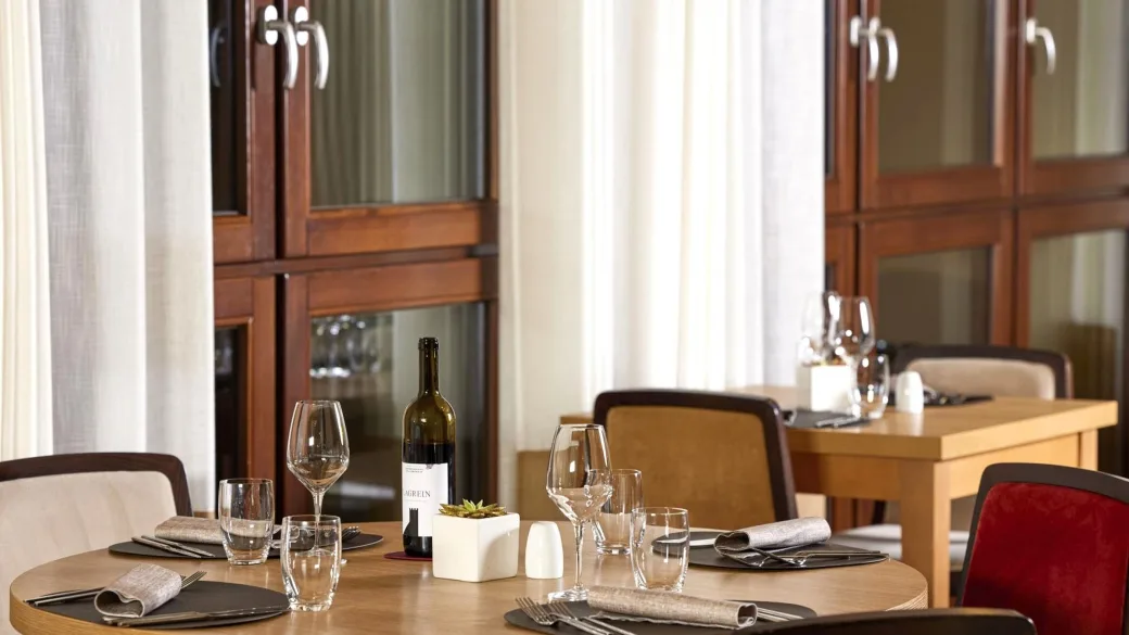 Tavolo del ristorante apparecchiato con calici e bottiglia di vino