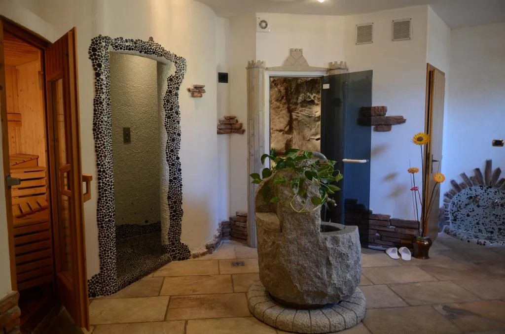 Area benessere con sauna in legno, bagno turco e fontana in pietra decorativa