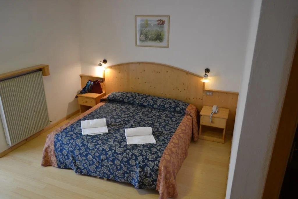 Camera matrimoniale con copriletto blu floreale, testiera in legno e asciugamani sul letto