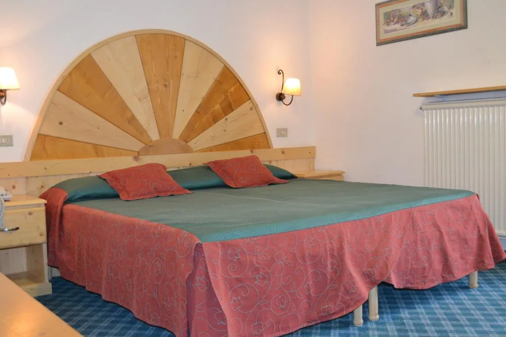 Camera con letto matrimoniale, testiera in legno a raggiera e moquette blu