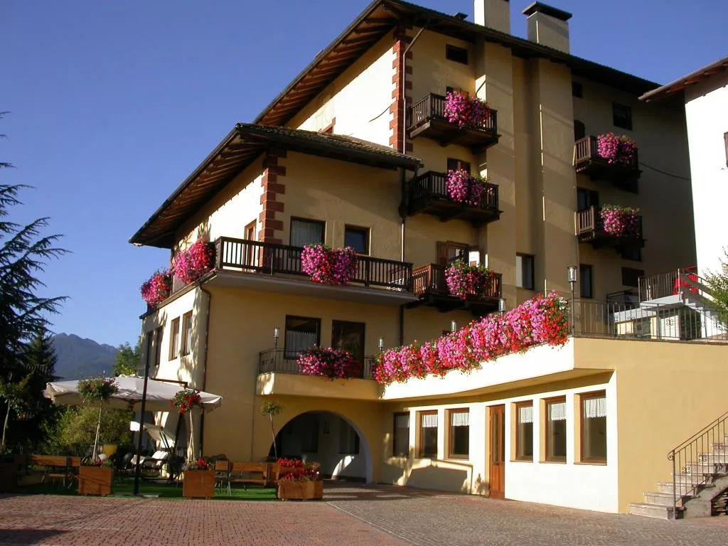 Esterno dell'hotel con balconi decorati da fiori rosa e area relax con ombrelloni