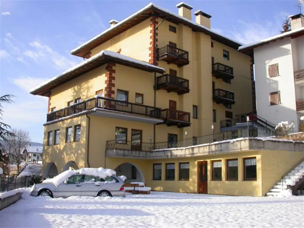 Esterno dell'hotel innevato con balconi in legno e auto parcheggiata nel piazzale