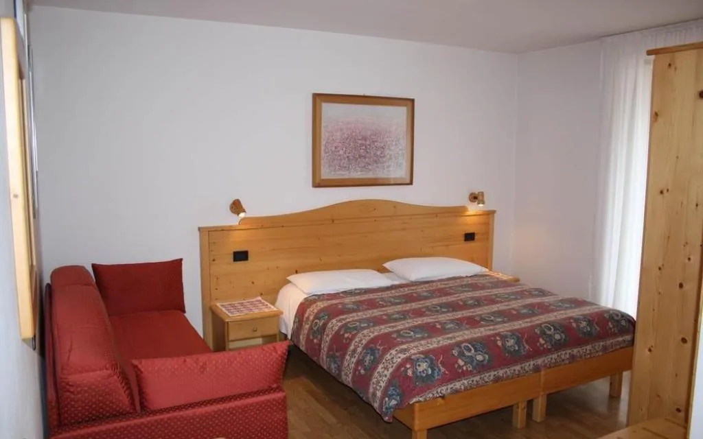 Camera con letto matrimoniale in legno e divano rosso