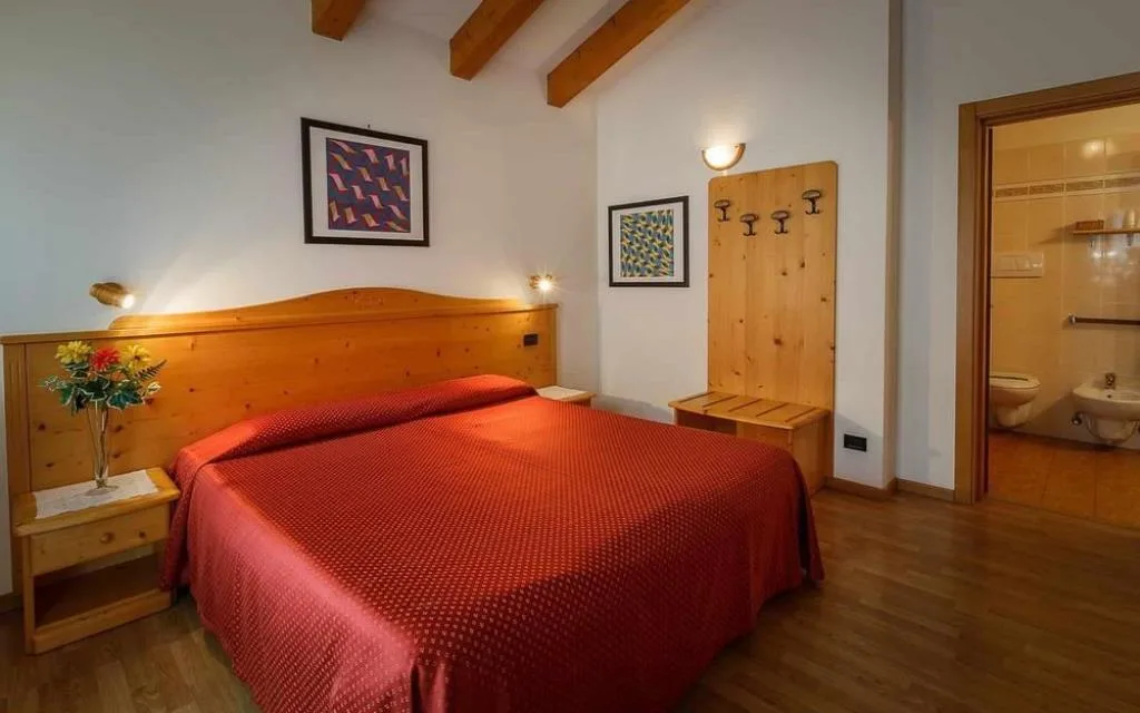 Camera matrimoniale con letto dal copriletto rosso e bagno privato attiguo